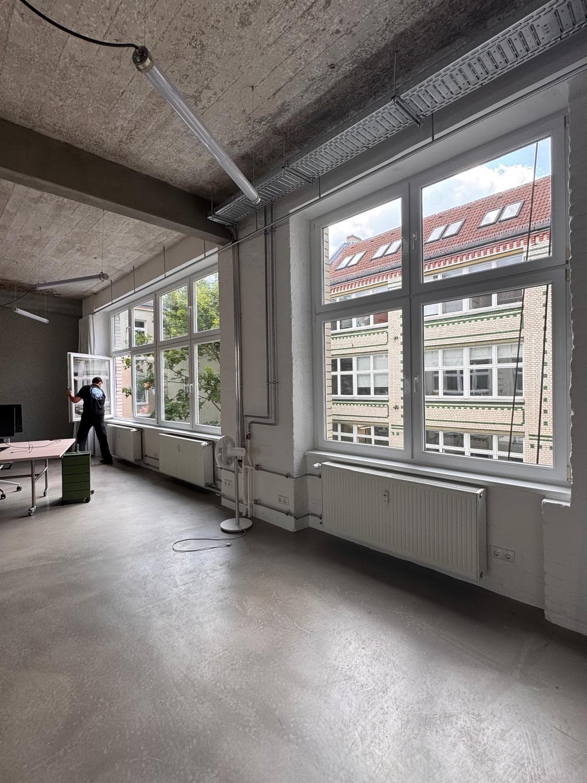 DDA-Mitarbeiter an einer langen Fensterfront in einem Büro mit hohen Decken