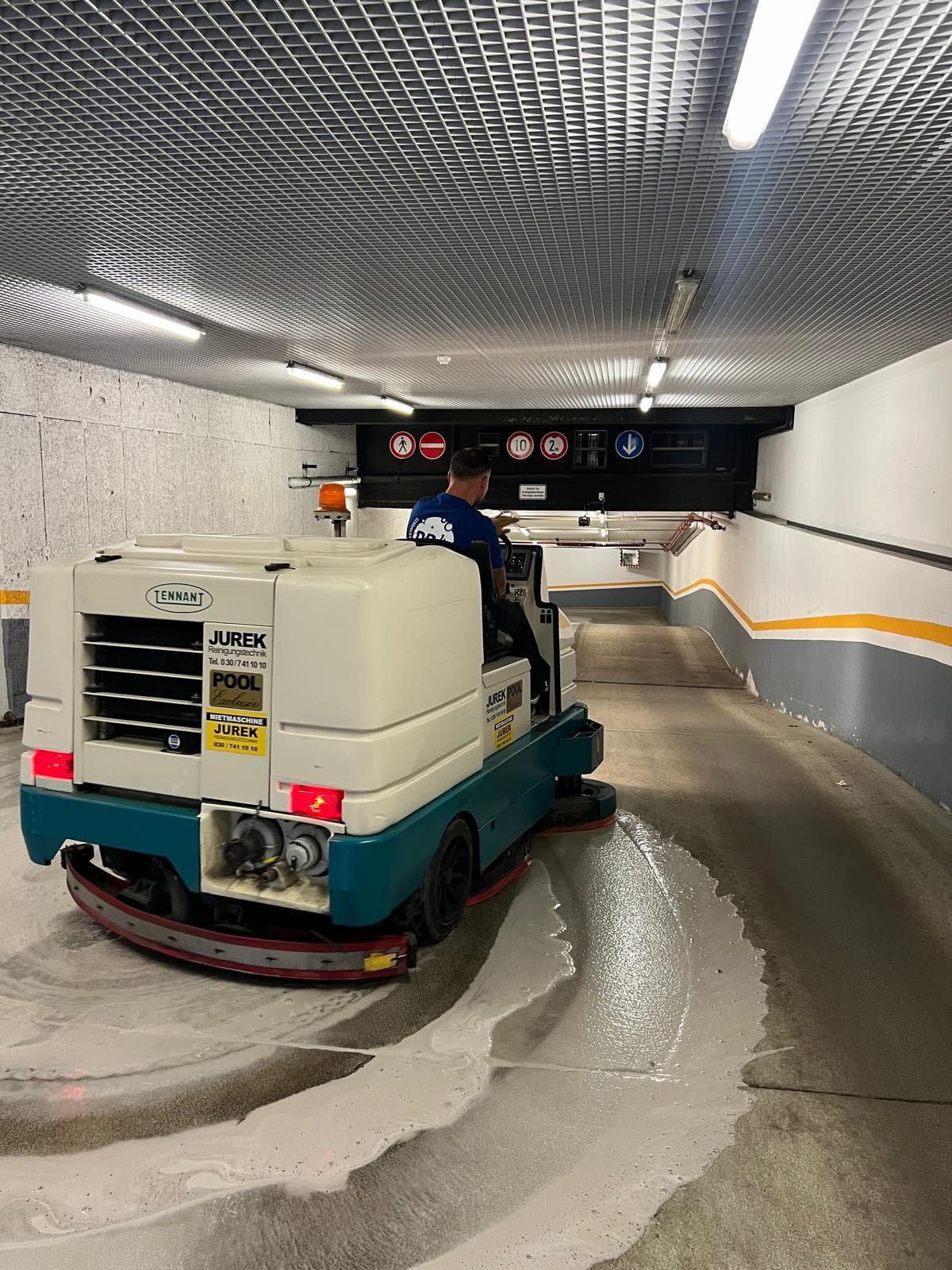 DDA-Mitarbeiter fährt eine Aufsitz-Reinigungsmaschine auf einer Tiefgaragenrampe